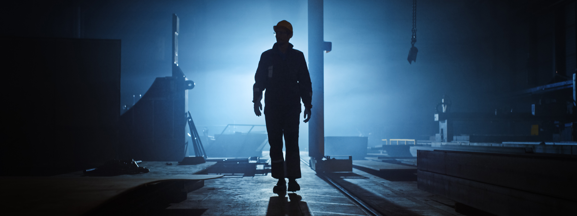 Silhouette of man in factory with light behind him
