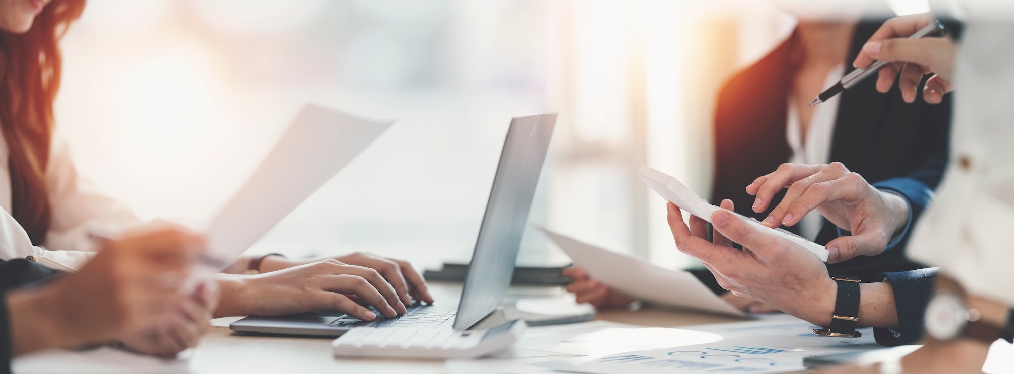Business meeting people sitting at a desk with laptop, calculator and paperwork